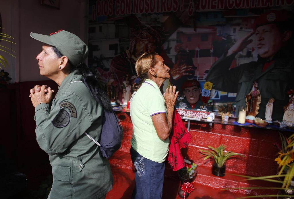 Women pray at altar to "St Hugo Chavez"