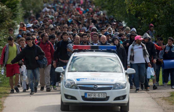 Migrants walk behind a police car in the Hungarian border town of Hegyeshalom toward the border of Austria