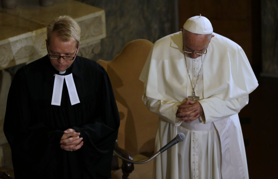 Pope Francis, right, prays with Rev Jens-Martin Kruse during a visit to the Lutheran church, in Rome, on Sunday