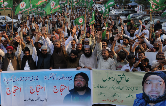 Supporters of Mumtaz Qadri rally behind a banner stating that the sentence is unacceptable