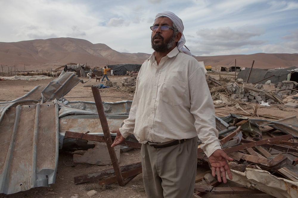 Farmer stands in the ruins of his house 